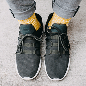 Männerfüße in schwarzen Schuhen mit gelben Socken
